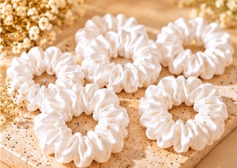 White hair scrunchies arranged on a warm beige surface

